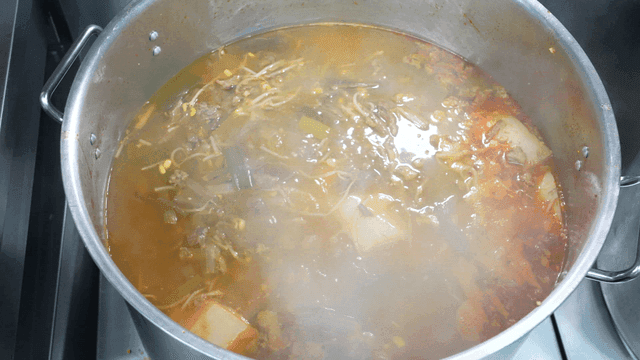 Beef stew boiling in large pot