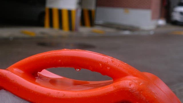 Orange rubber cone handle on an alley on a rainy day