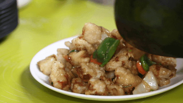 Plate containing stir-fried vegetables and sweet and sour pork