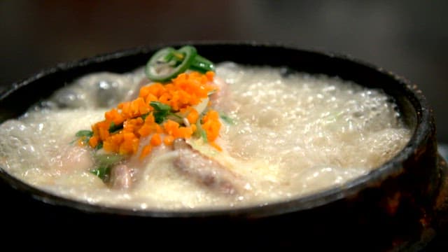 파와 얇게 썬 당근과 함께 끓고 있는 삼계탕