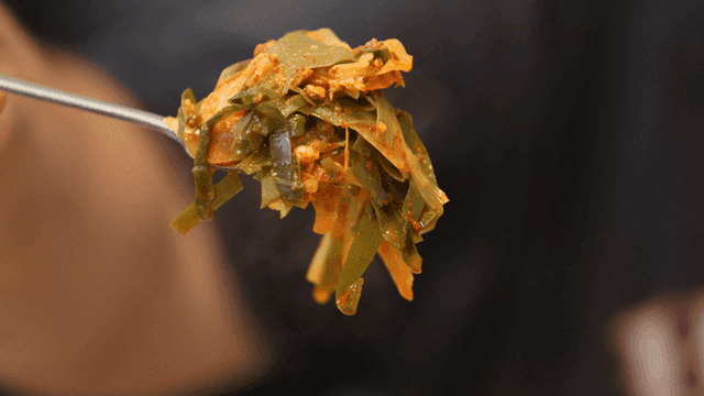 파가 담긴 김이 나는 부대찌개를 든 숟가락