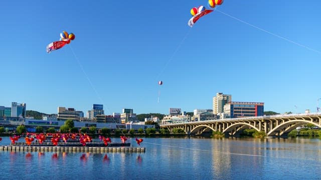 Bright morning by the river with colorful balloons floating above a cityscape