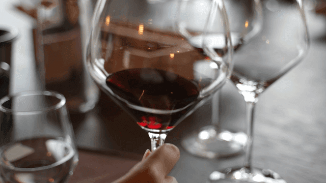 Hand holding and shaking glass of red wine