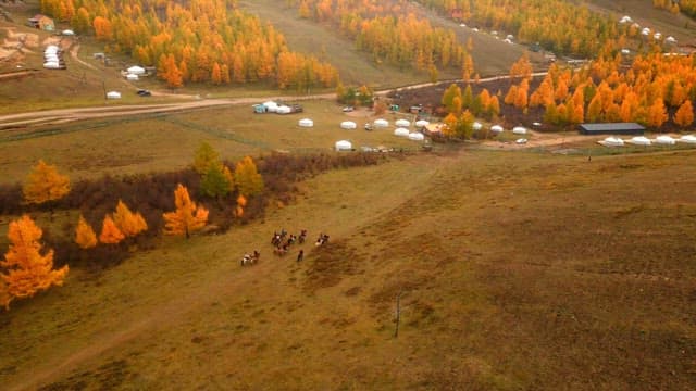 Riders on horseback in a scenic autumn landscape