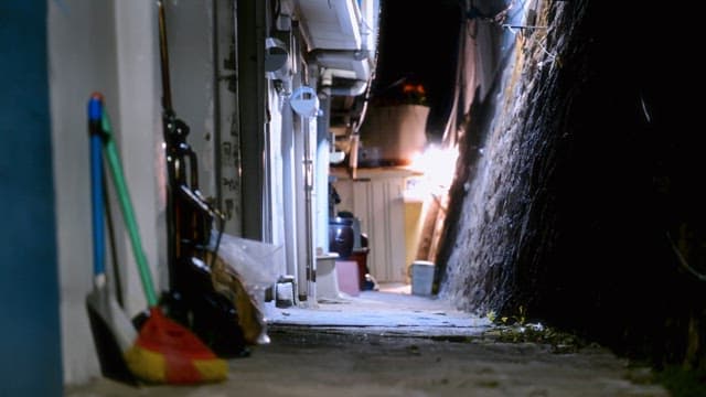 Narrow alleyway with cleaning tools at night