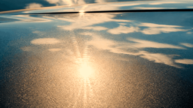 Sunlight and clouds reflected on car hood