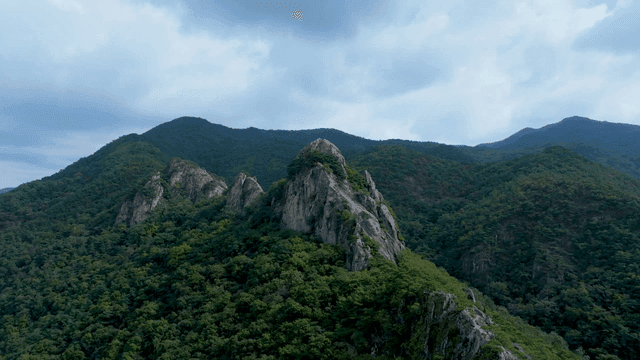 구름 낀 하늘 아래 푸른 바위 산봉우리 