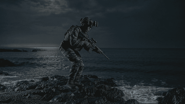Soldiers patrolling rocky beach at night