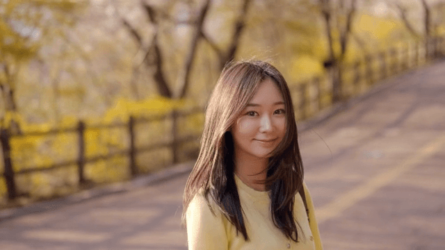 햇살이 비치는 공원 길을 걷는 여성