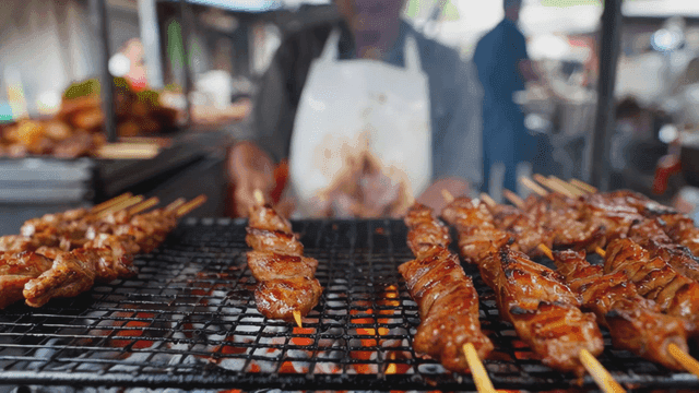 Street vendor grilling skewered meat