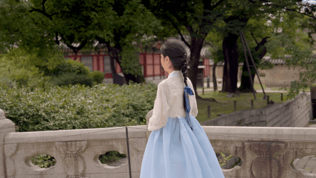 Woman in hanbok walking in a traditional garden