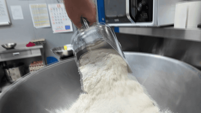 Person pouring flour into large mixing bowl