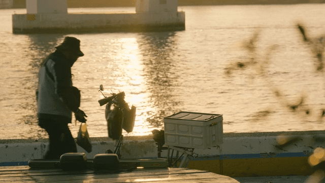 Man and bicycle along river at sunset