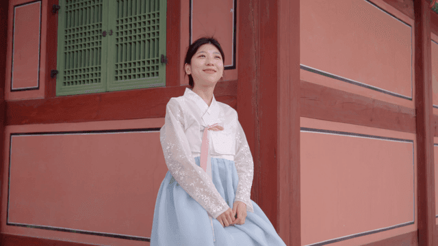 Woman in hanbok smiling at a traditional site