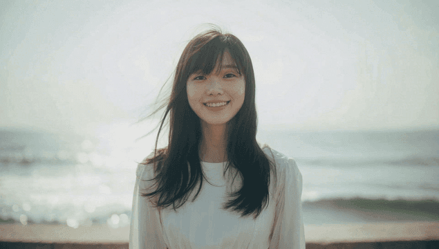 바닷가에서 정면을 보고 미소 짓는 여성