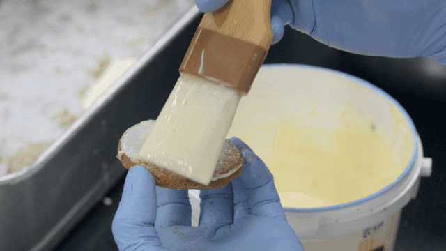 Hands applying glaze to cookies with brush