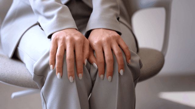 Woman in suit with her hands on her knees