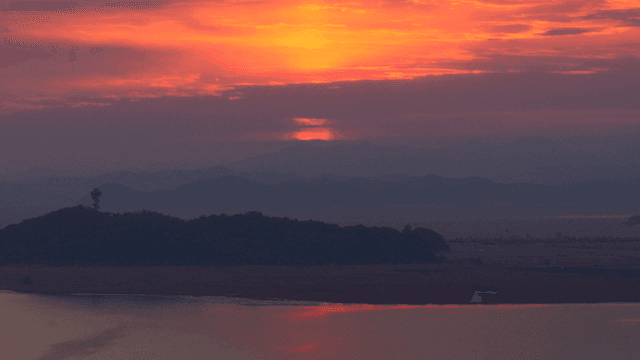 멀리 언덕이 보이는 고요한 강의 일몰