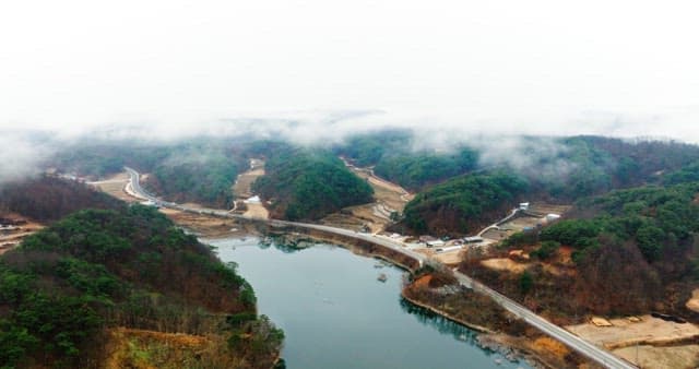 Misty Lakeside Road Amidst Forested Hills