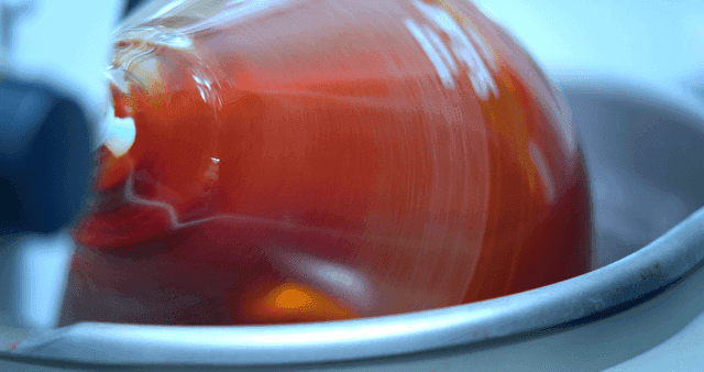 Swirling red liquid inside a laboratory glass vessel
