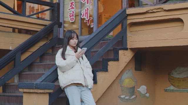 계단에 기대어 스마트폰을 사용하는 여자