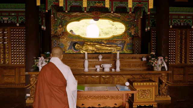 Monk in a temple with a golden Buddha statue
