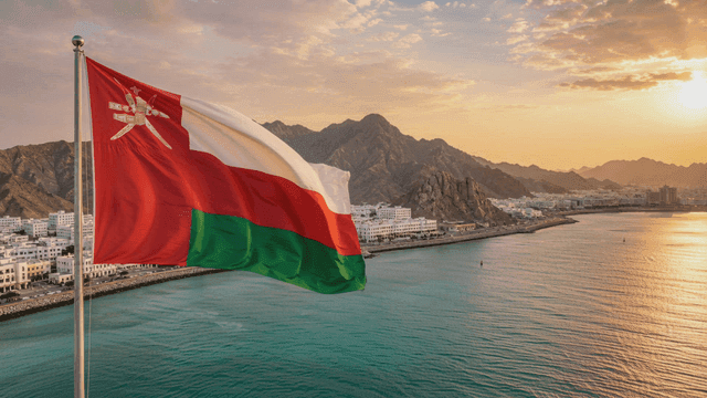 Omani flag waving by the seaside at sunset