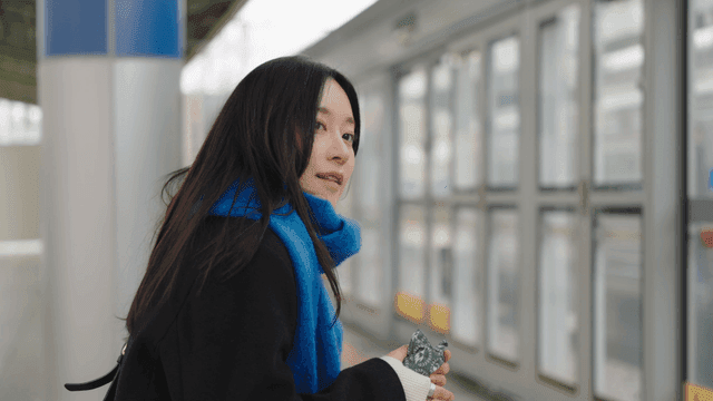 Woman waiting on a train station platform with a hot pack