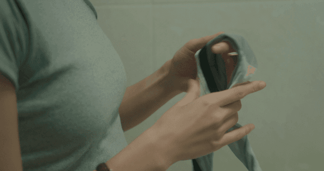 Schoolgirl wiping armpit sweat with a handkerchief while looking in a mirror