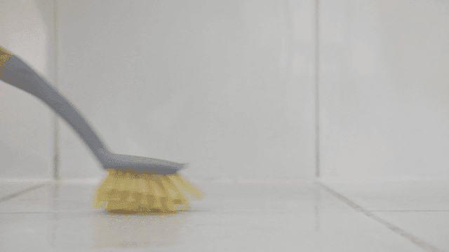 Cleaning a tiled floor with a brush