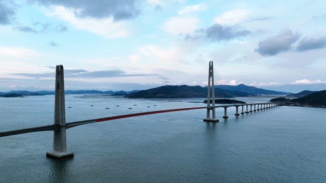 Long bridge over a calm sea with mountains