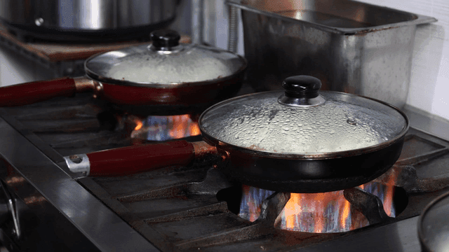 Two pans with lids on a stove
