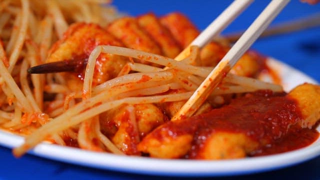 Chopsticks holding spicy fish cake and bean sprouts