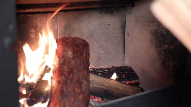 Person adding a log to a fireplace