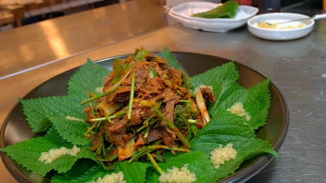 주방에서 깻잎과 함께 플레이팅되는 고기 무침