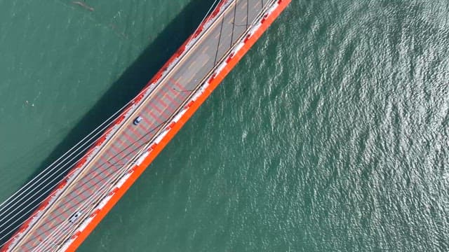 Cars driving on a red bridge over water