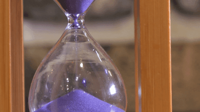 Purple sand flowing in an hourglass