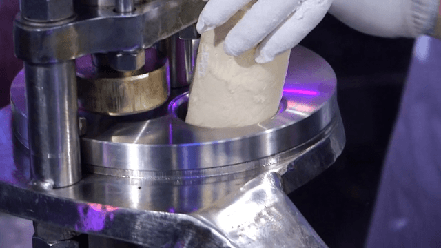 Putting the dough into a machine with the gloved hand