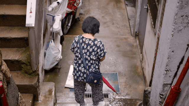 An elderly woman walking down stairs in an alley