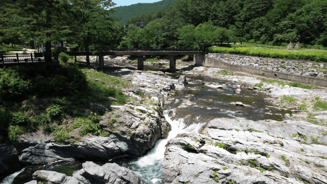 Clear valley stream flowing between rocks under bridge