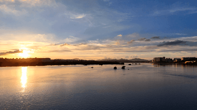Tranquil river sunset against backdrop of city landscape.