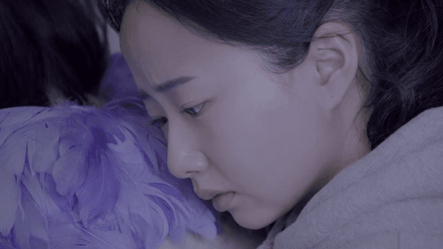 보라색 깃털 옷을 입은 사람 뒤에 기대어 있는 여성