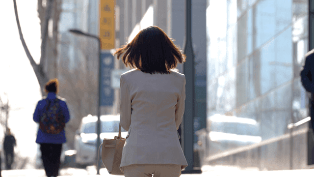 Back view of working woman walking on city street