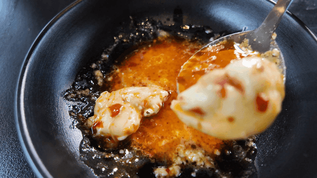 Spoon scooping rice cakes of cheese mala hot pot