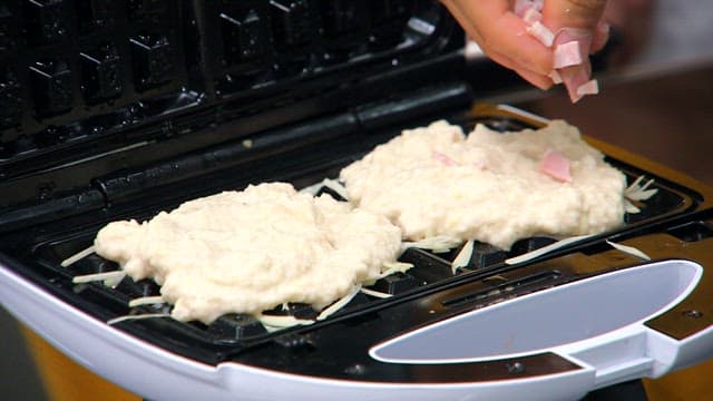 와플 기계 위 감자 반죽에 잘게 썬 베이컨을 토핑하는 모습