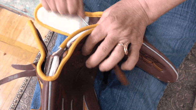 Craftsman threading lace into baseball glove