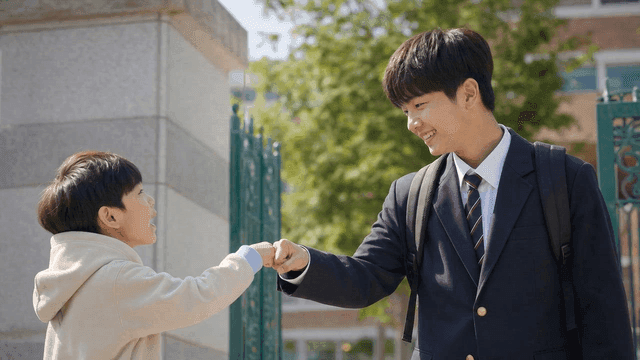 Boy exchanging fist bumps with student in school uniform