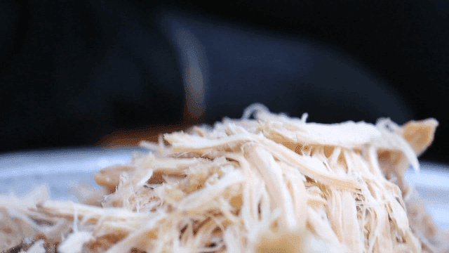 Shredding chicken with gloved hands