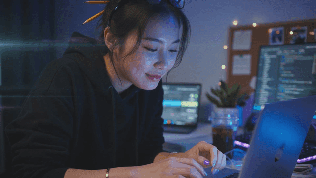 Woman coding on laptop at night
