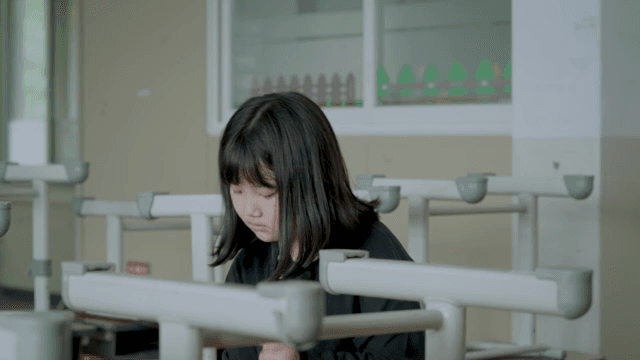 Child cleaning the classroom while deep in thought
